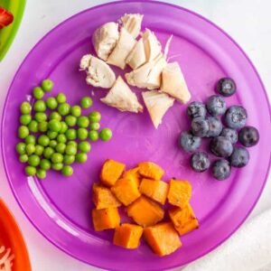 Image of a plate of food for a child (peas, sweet potatoes, blueberries, and cut up chicken). Photo credit: https://www.familyfoodonthetable.com/healthy-toddler-finger-food-ideas/